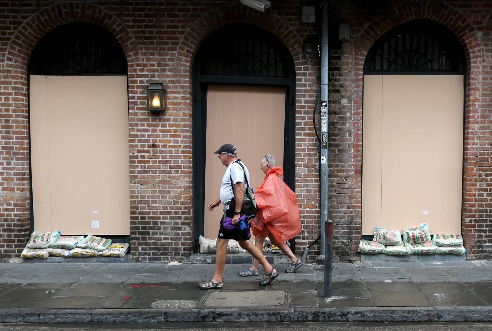 People walk past a boarded up building in the French Quarter as Tropical Storm Barry approaches land in New Orleans