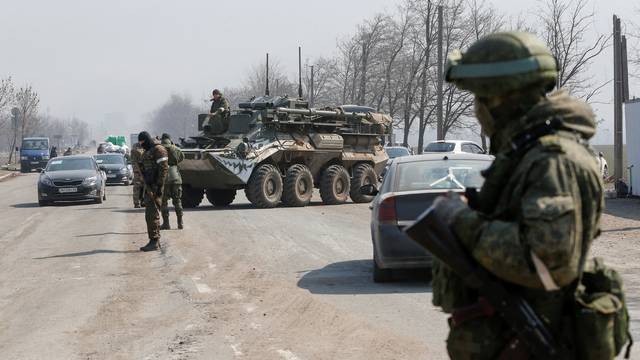 Service members of pro-Russian troops stand guard at a checkpoint in the besieged city of Mariupol