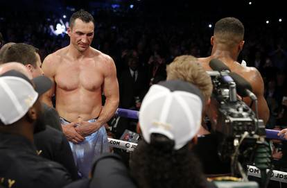 Anthony Joshua speaks to the fans after winning the fight as Wladimir Klitschko looks on dejected