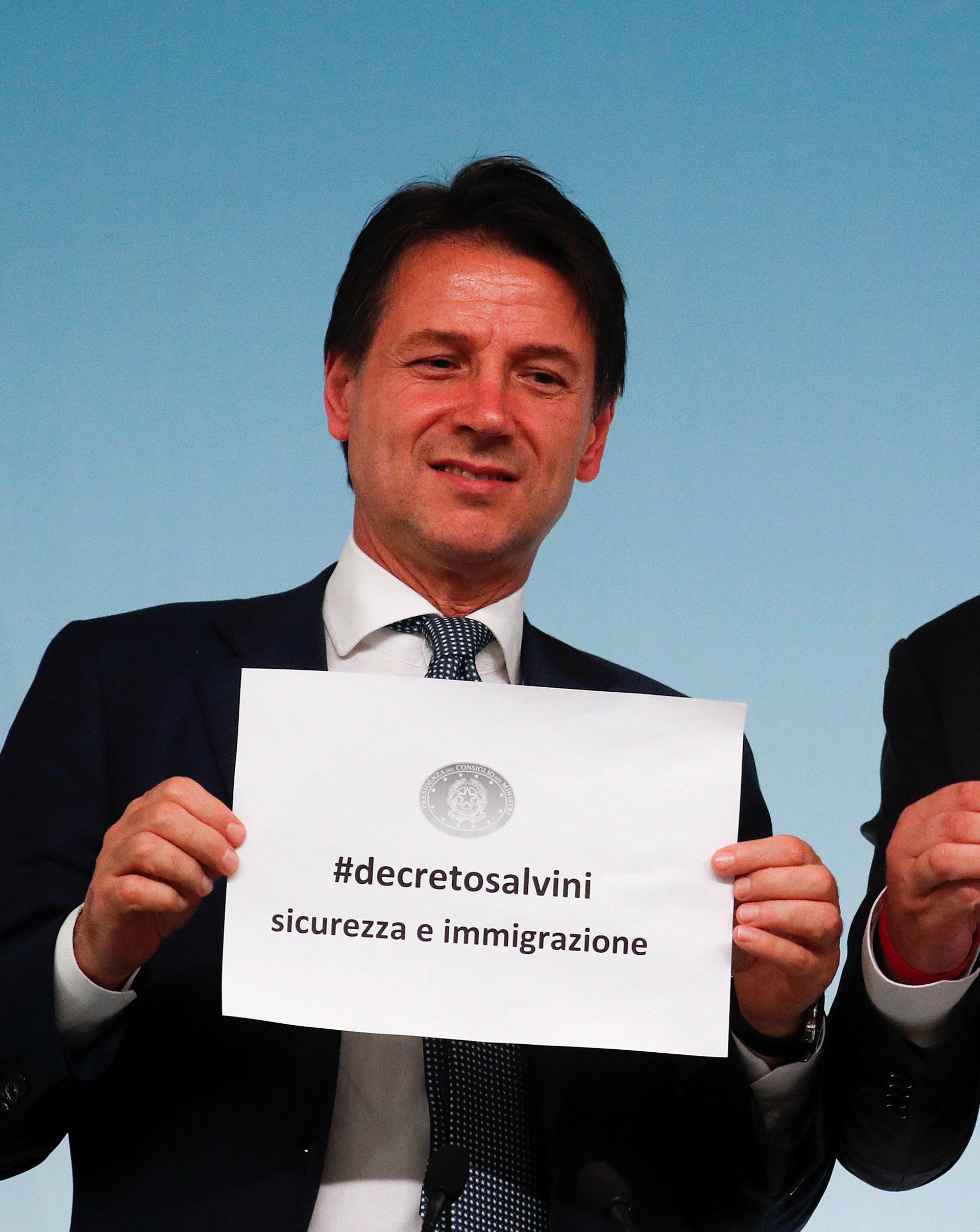 Italy's Prime Minister Conte and Interior Minister Salvini hold up pieces of paper with the name of the new decree written on them during a news conference at Chigi Palace in Rome