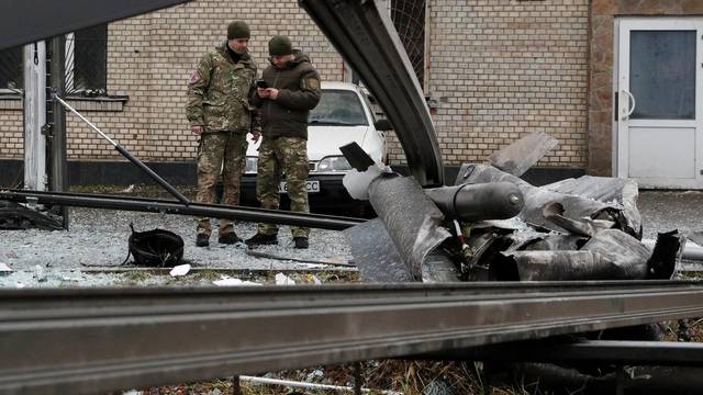 Police officers inspect the remains of a missile that fell in the street in Kyiv