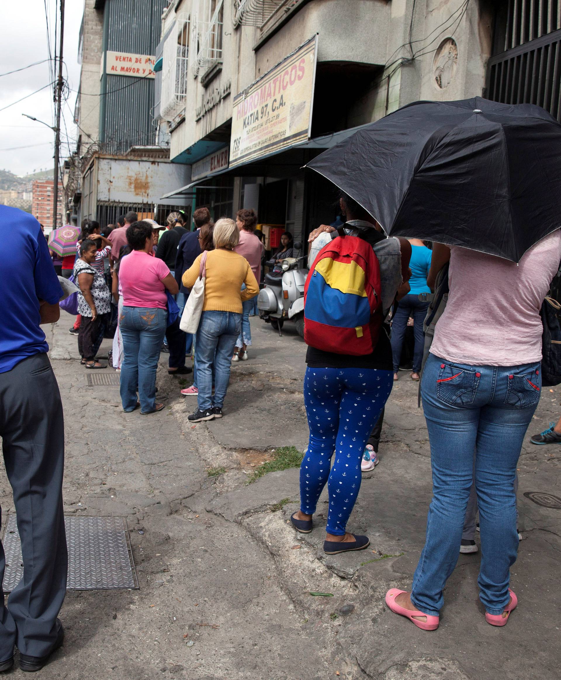 People line up to withdraw cash at an ATM machine in Caracas