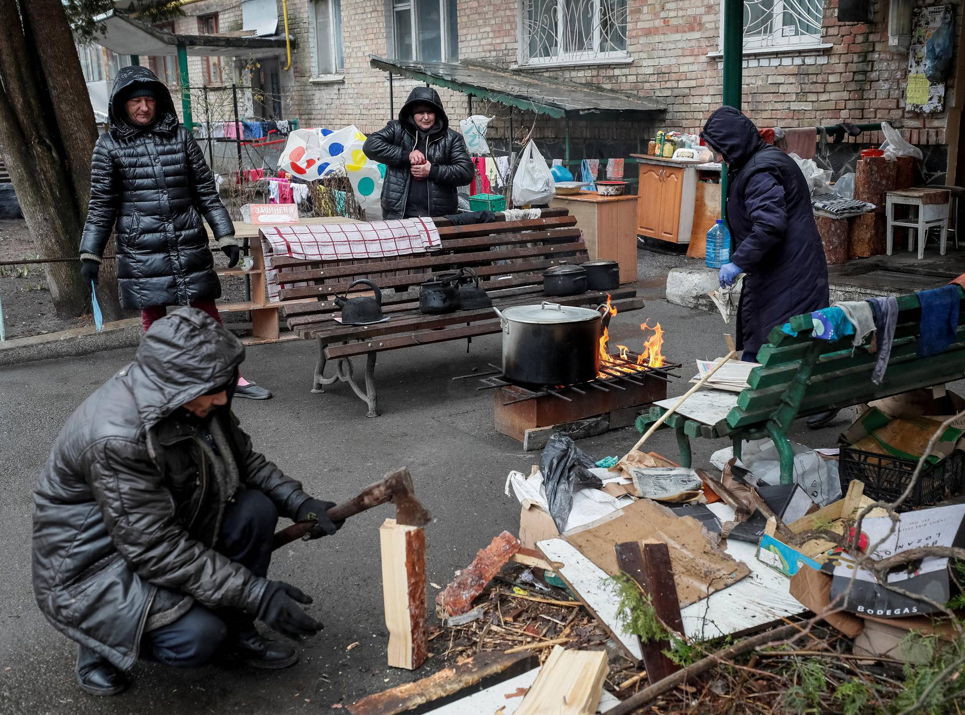 Locals residents cook food on a fire in the yard of their house in Bucha