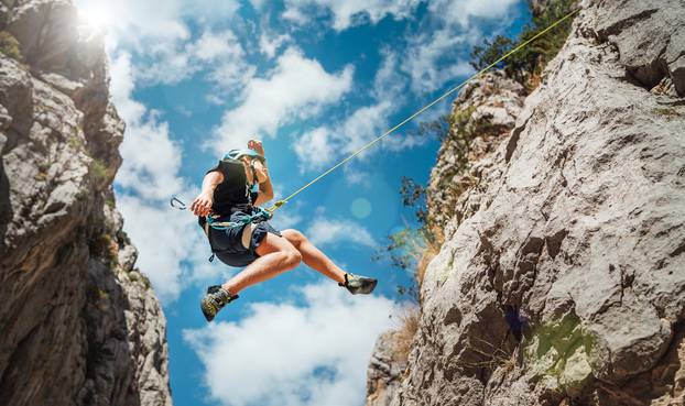 Climber,Teenage,Boy,In,Protective,Helmet,Jumping,On,Vertical,Cliff