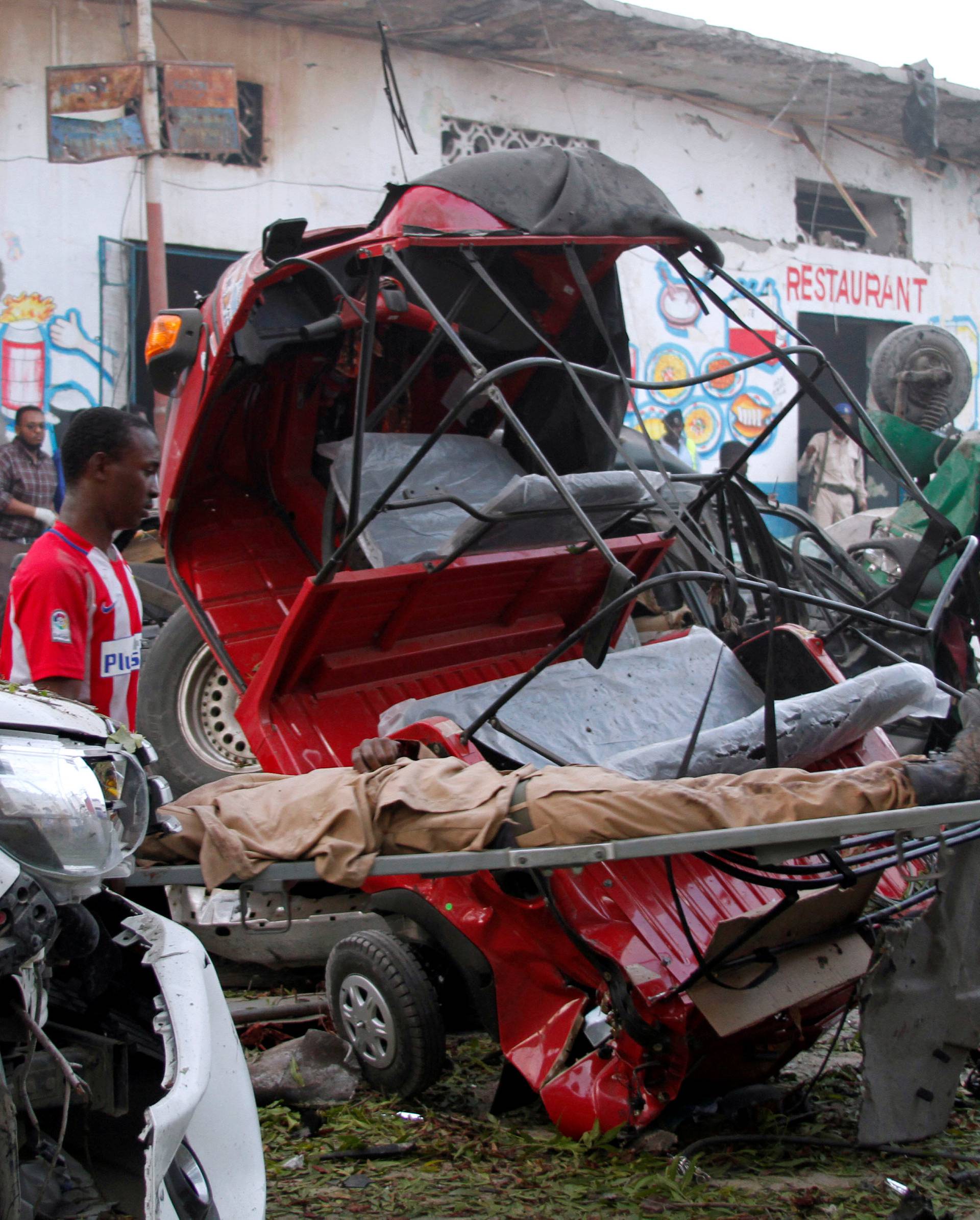 Civilians carry a man injured from a suicide car bombing at the gate of Naso Hablod Two Hotel in Mogadishu