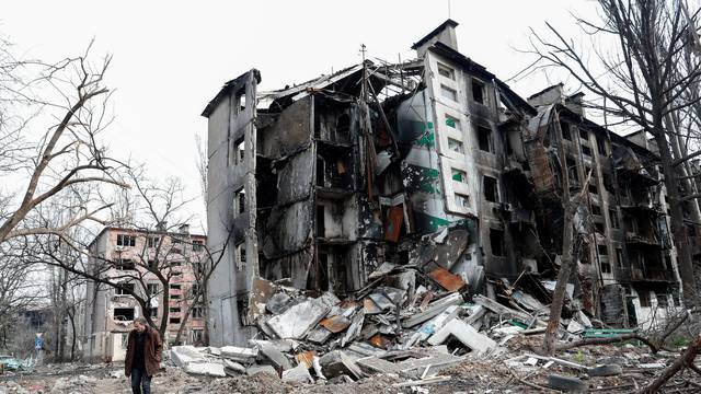 A man walks near a destroyed residential building in Mariupol