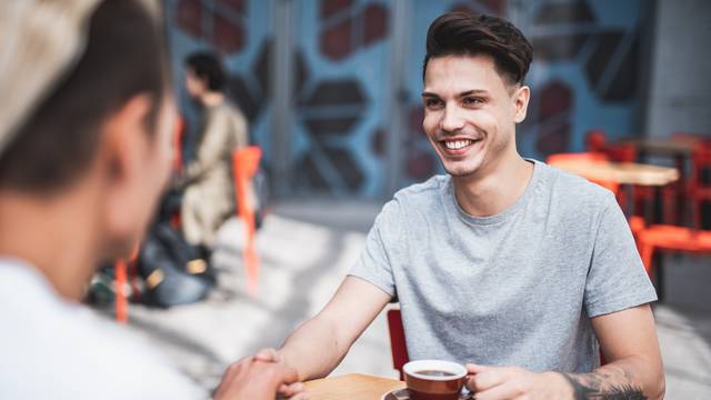 Positive male drinking mugs of coffee together