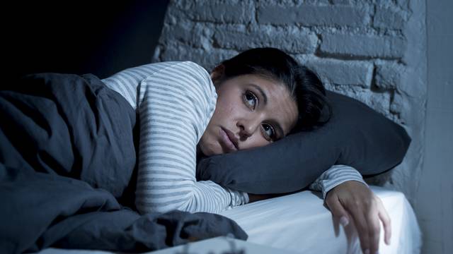 woman in bed late night trying to sleep suffering insomnia