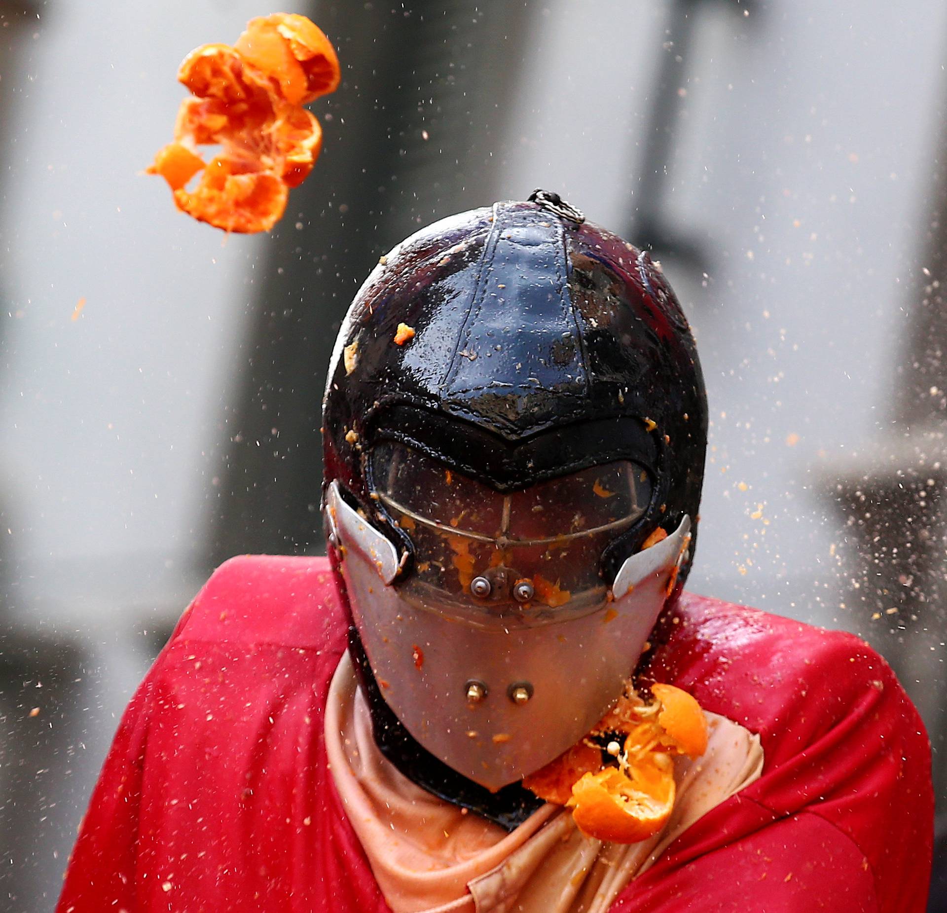A member of a team is hit by oranges during an annual carnival battle in the northern Italian town of Ivrea