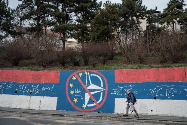 A woman walks past an anti-EU and NATO graffiti in Belgrade