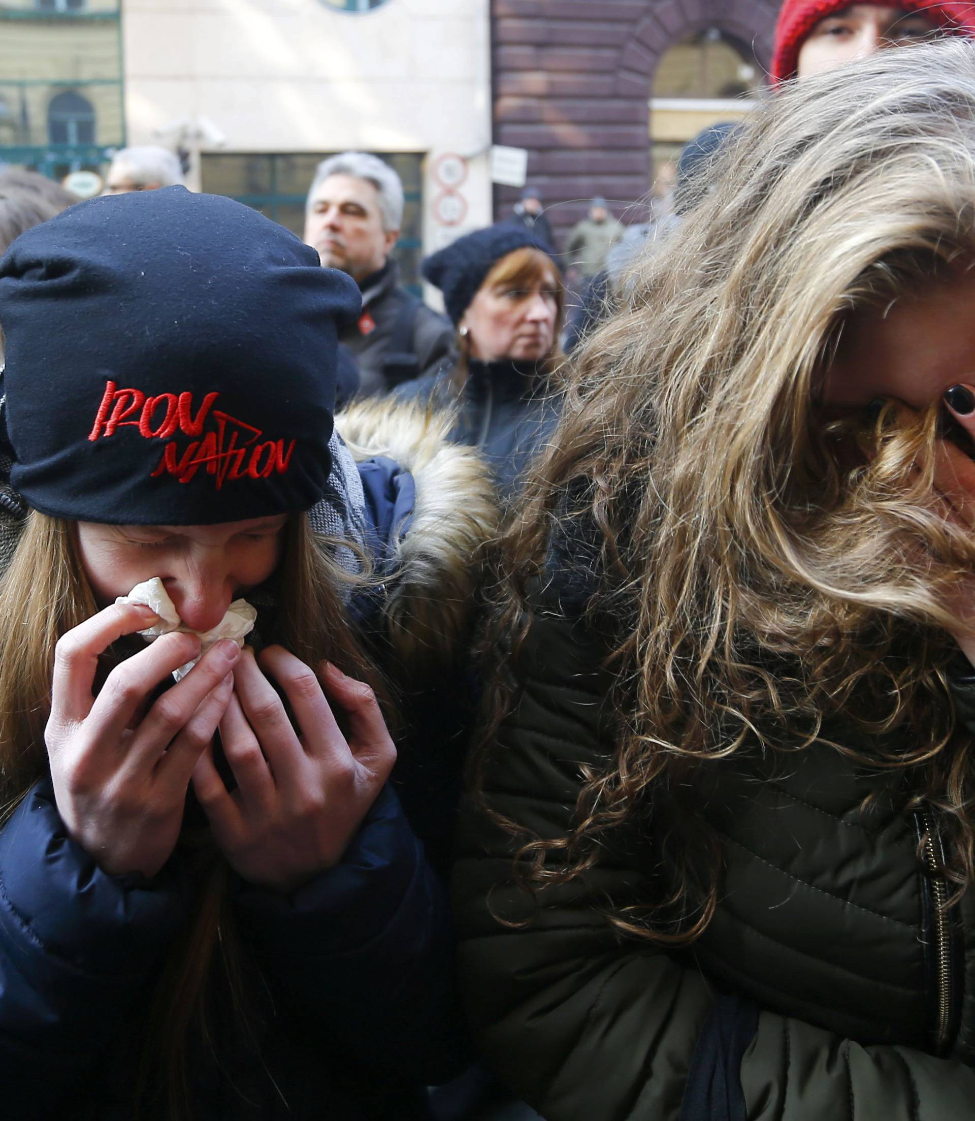 People cry in front of a school building in Budapest