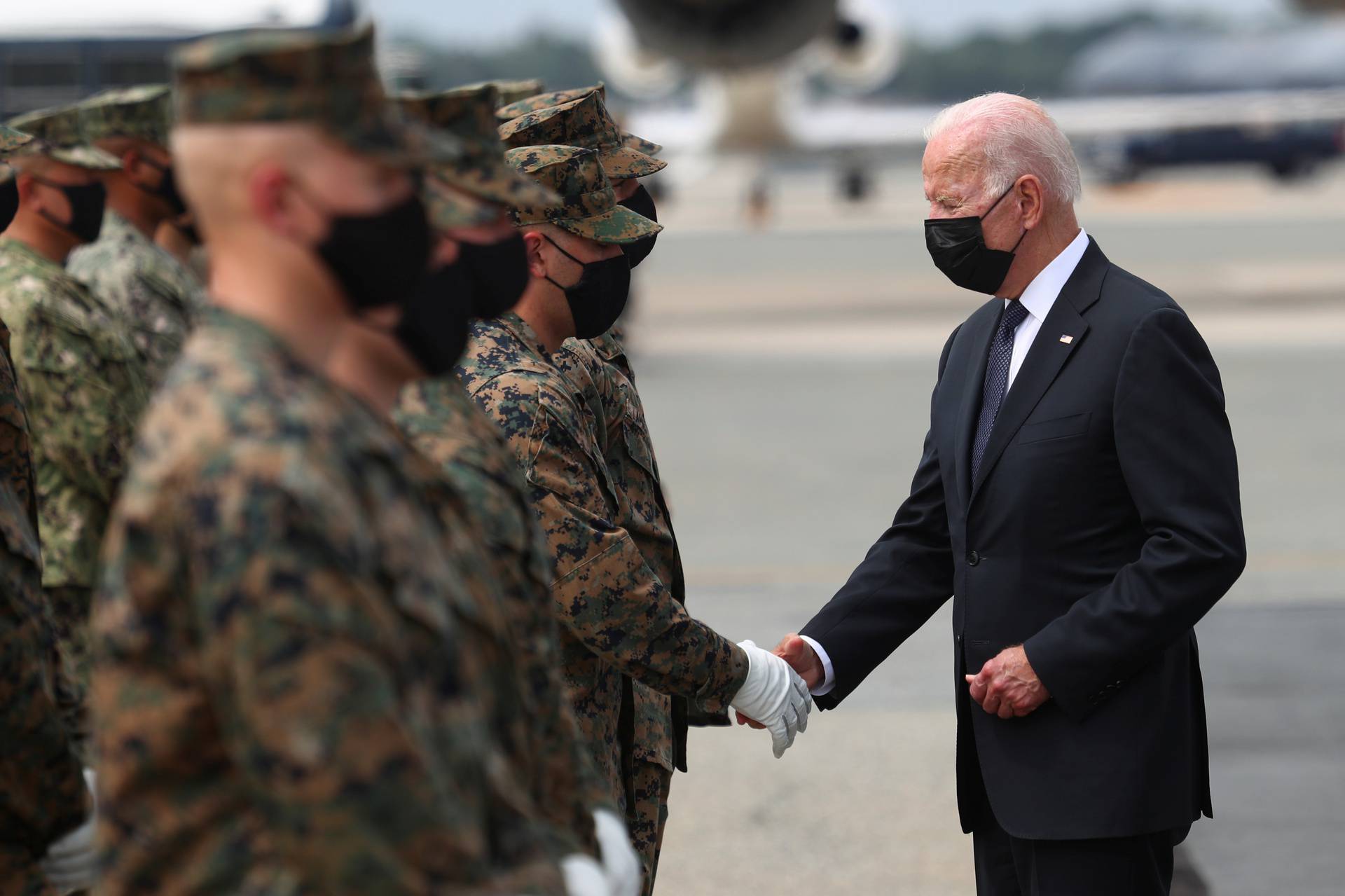 U.S. President Joe Biden hands challenge coins to the members of the U.S. Marine Corps Honor Guard before boarding Air Force One