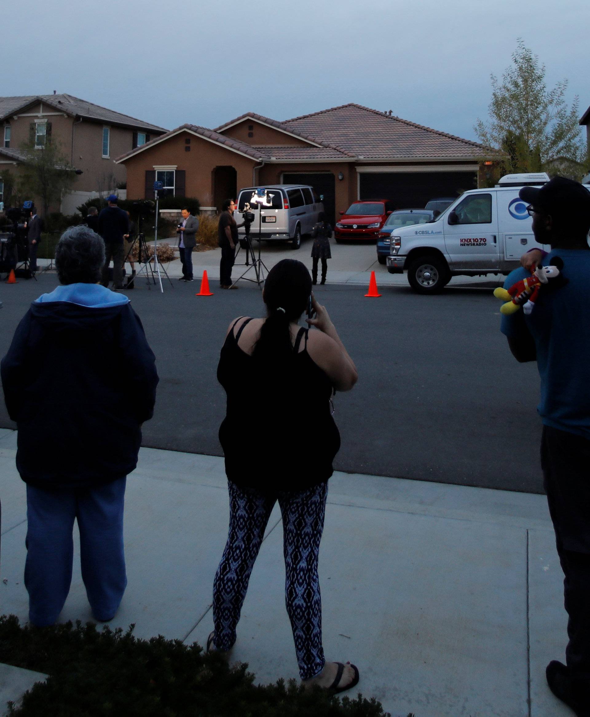 Neighbors stand and watch news crews outside the home of David Allen and Louise Anna Turpin in Perris, California