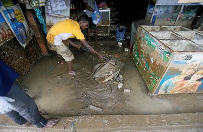 A man cleans his shop which was affected by the floods in Biyagama