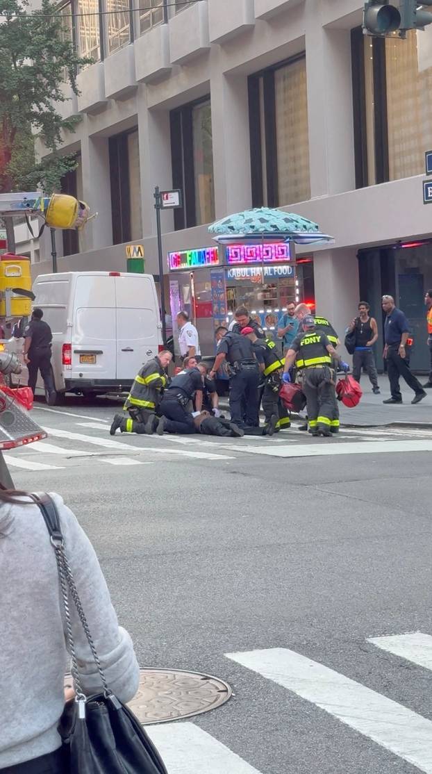 Police officers try to rescue an injured man next to a Midtown Manhattan skyscraper, in New York