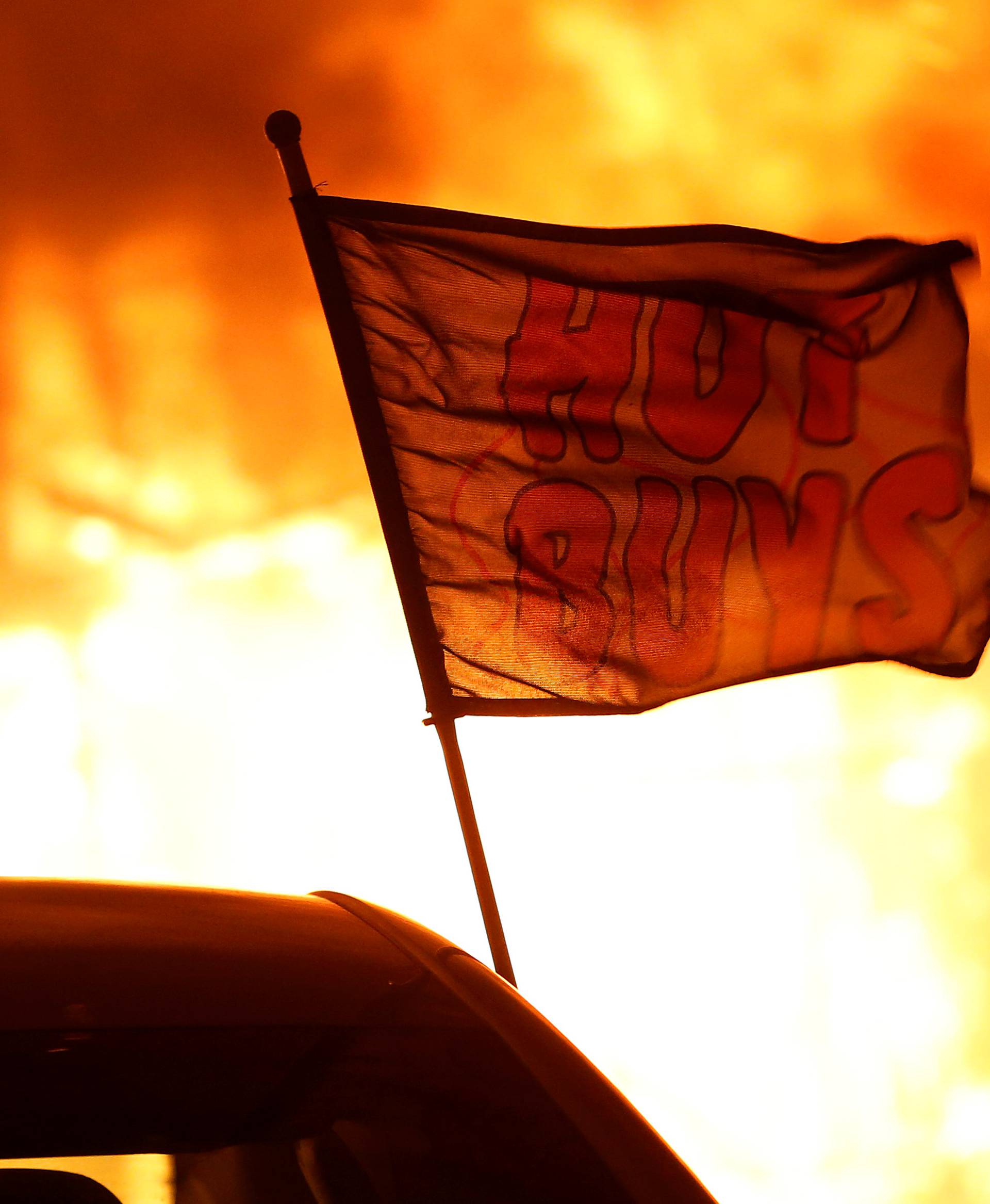 A flag is seen at a burning used car dealership during the Camp Fire in Paradise
