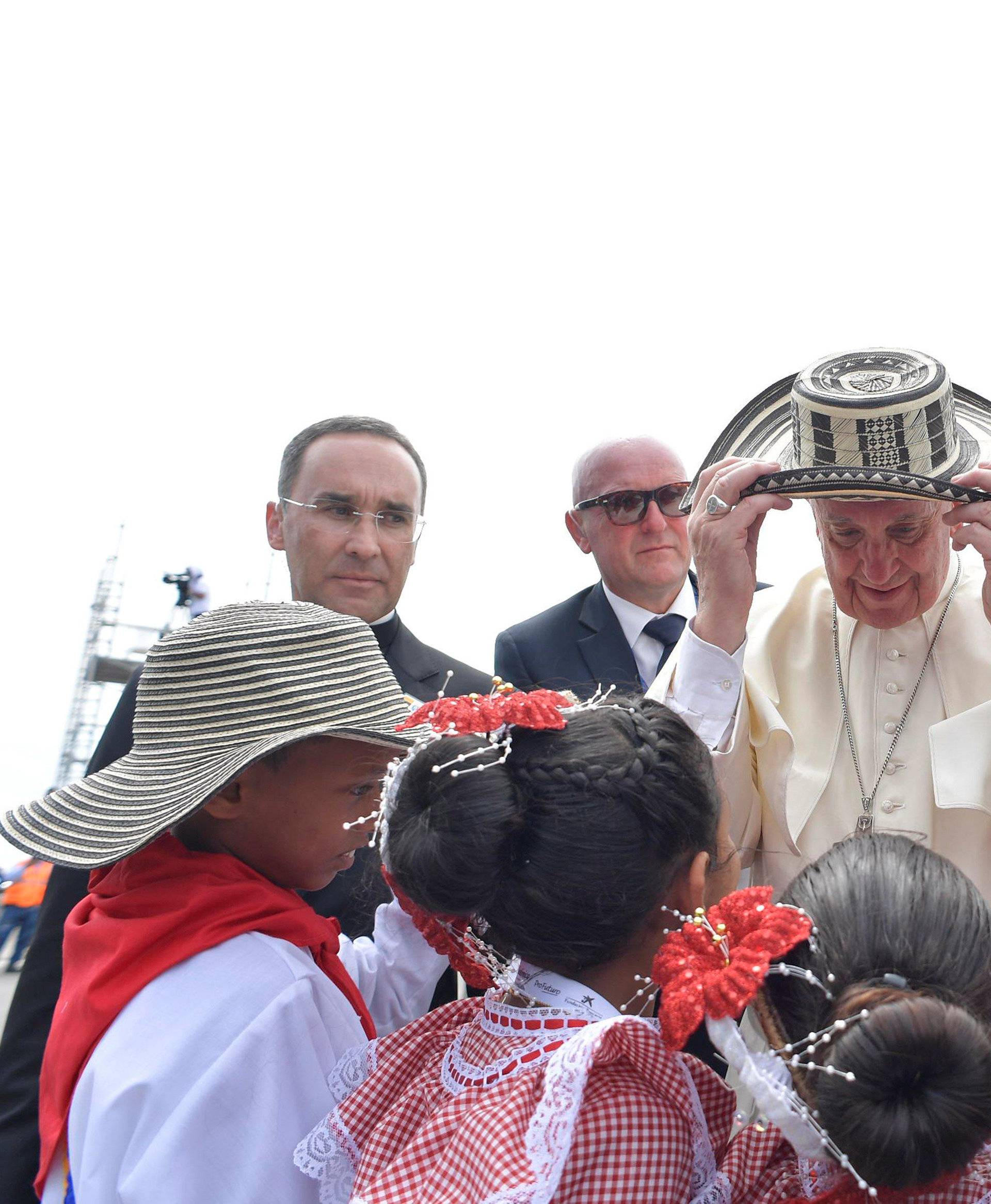 Pope Francis is presented with a hat as he arrives at the Cartagena airport