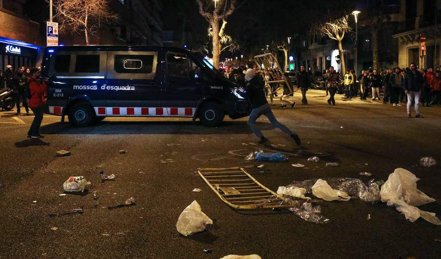 A protestor throws a barrier at a Catalan police van during skirmishes after former regional president Carles Puigdemont was detained in Germany,  in Barcelona