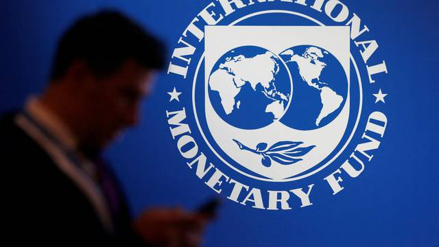 FILE PHOTO: A participant stands near a logo of IMF at the International Monetary Fund - World Bank Annual Meeting 2018 in Nusa Dua