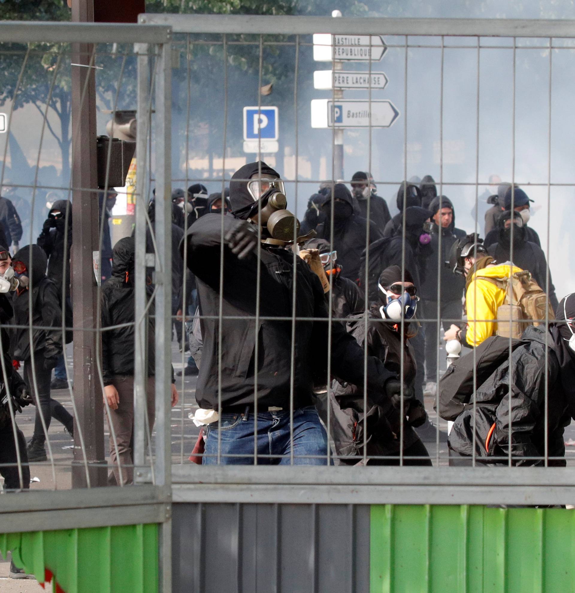 Tear gas floats around masked protesters during clashes with French CRS riot police at the May Day labour union rally in Paris