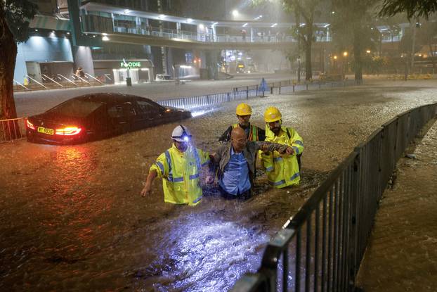 Drainage workers assist a driver stranded due to flooding to a safe place, during heavy rain in Hong Kong