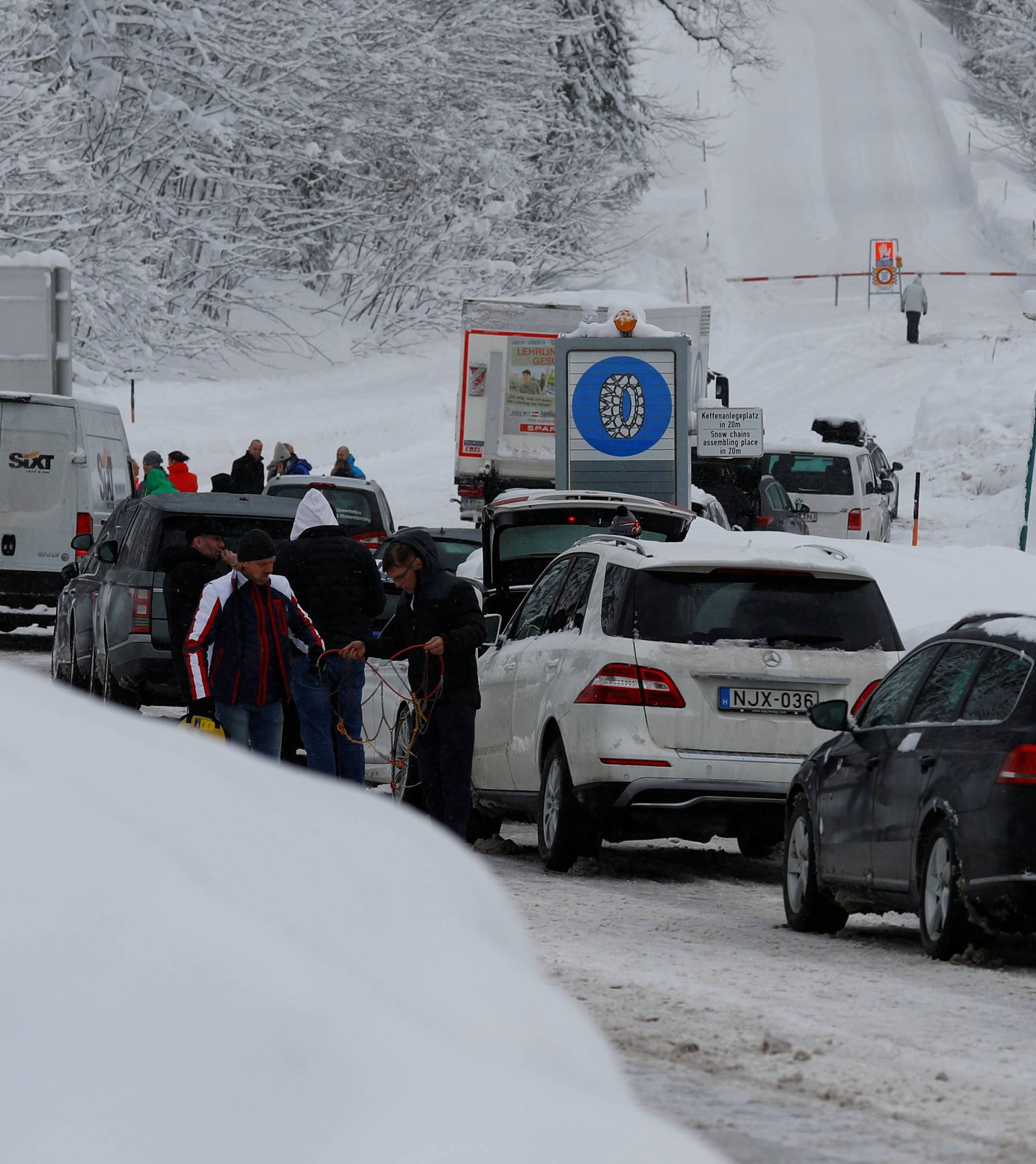 Tourists wait on a closed road after heavy snowfall near Obertauern