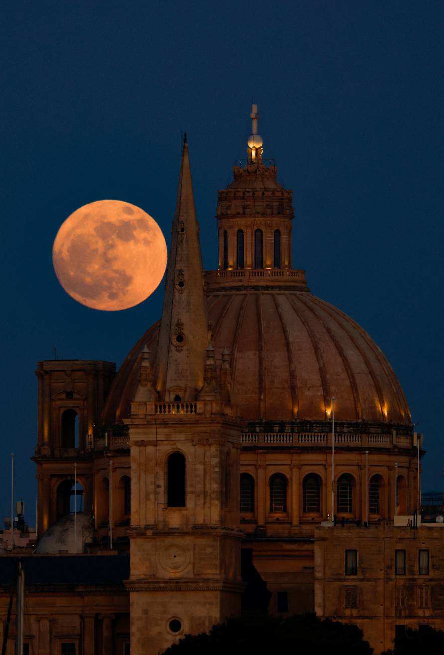 A full moon known as the Strawberry Moon rises behind St Paul's Anglican Cathedral and the Basilica of Our Lady of Mount Carmel in Valletta