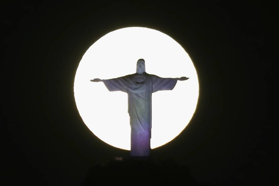 The super moon shines behind the Christ the Redeemer statue in Rio de Janeiro