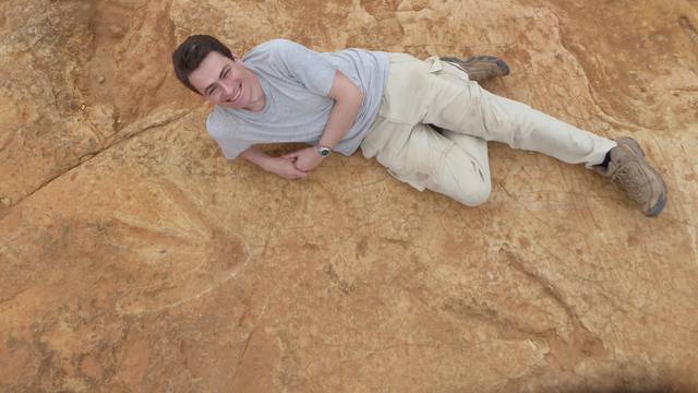 Fabien Knoll, Honorary Senior Research Fellow at the University of Manchester, lies next to the exceptionally large carnivorous dinosaur footprints found in Lesotho, Africa in this handout photo