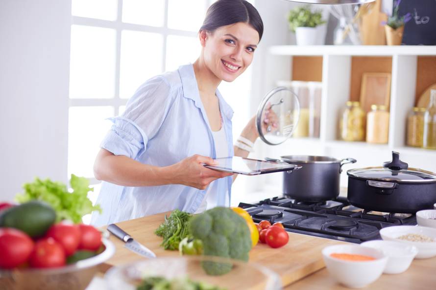 Young woman standing by the stove in the kitchen