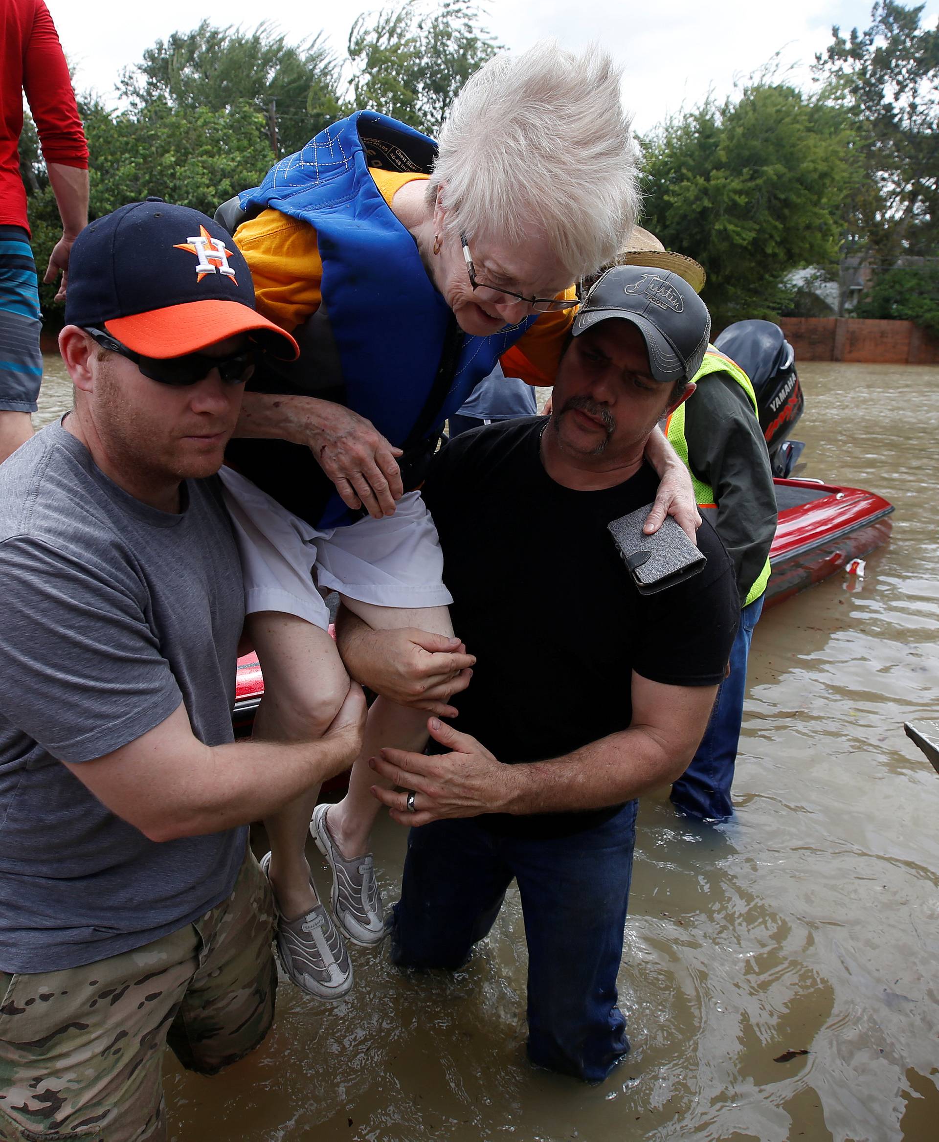 Volunteers help a woman from a rescue boat as it evacuates people from the rising waters of Buffalo Bayou following Hurricane Harvey in a neighborhood west of Houston