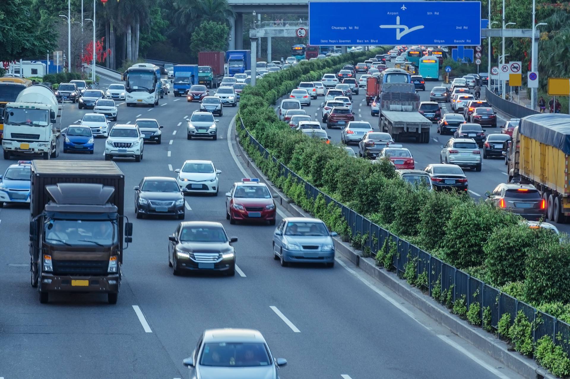 Gray day traffic jam, many cars on divided highway road in busy city. Urban view from above, air pollution by benzpyrene.