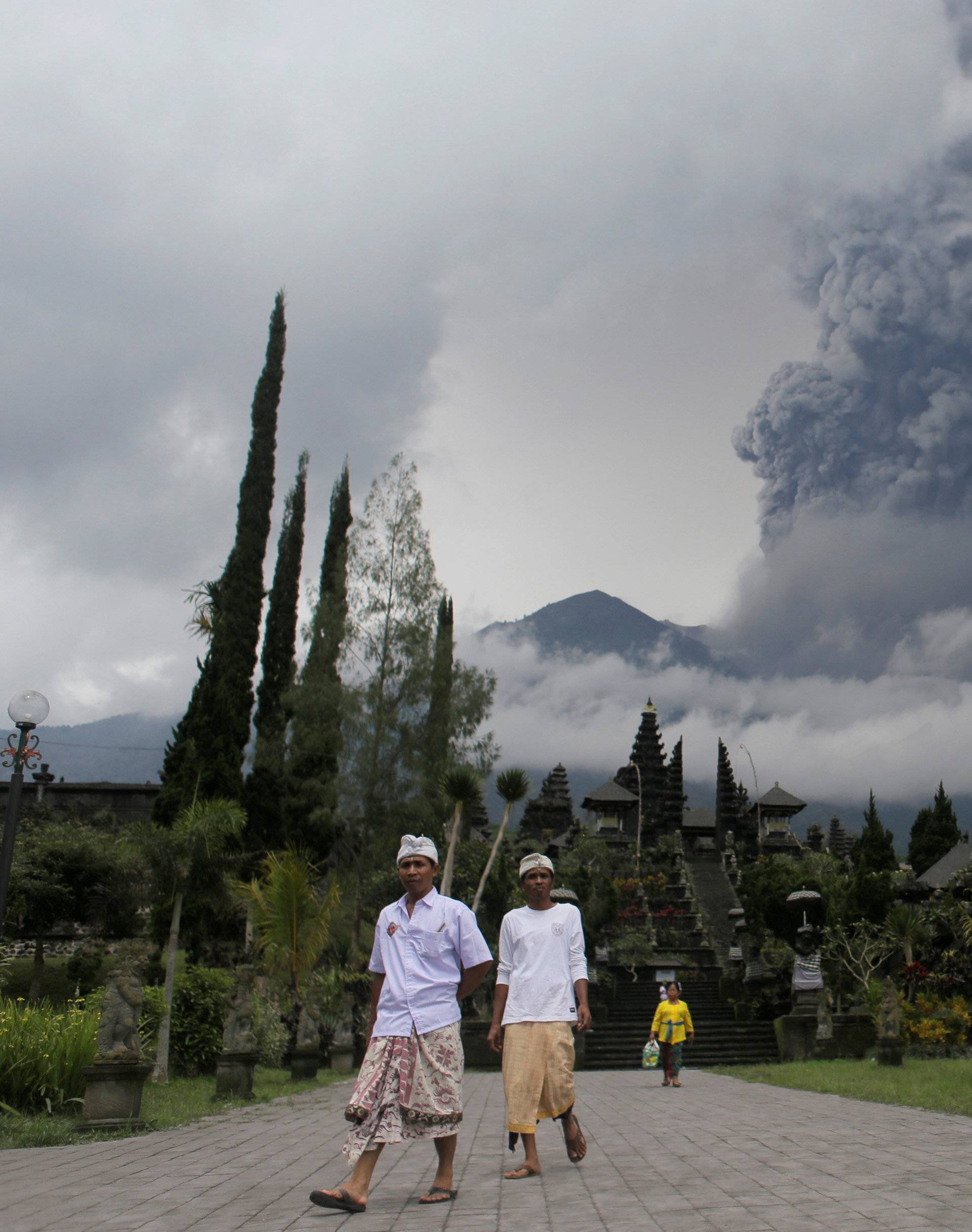 Balinese Hindus walk after praying as Mount Agung volcano erupts at Besakih Temple in Karangasem, Bali