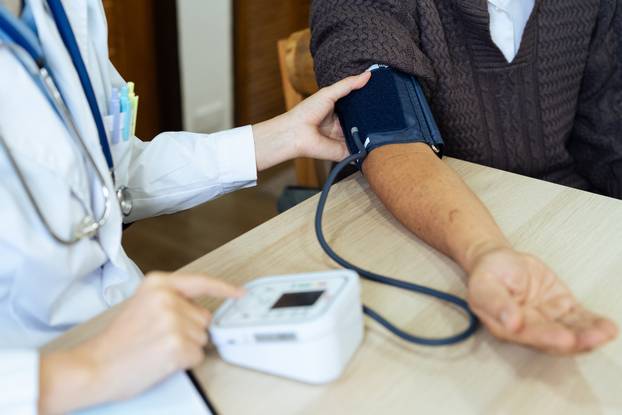 Doctor take care of elderly by helping to check their blood pressure