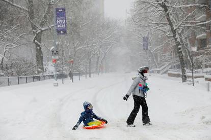 A woman drags a child on a sledge near Washington Square Park during a snow storm in New York