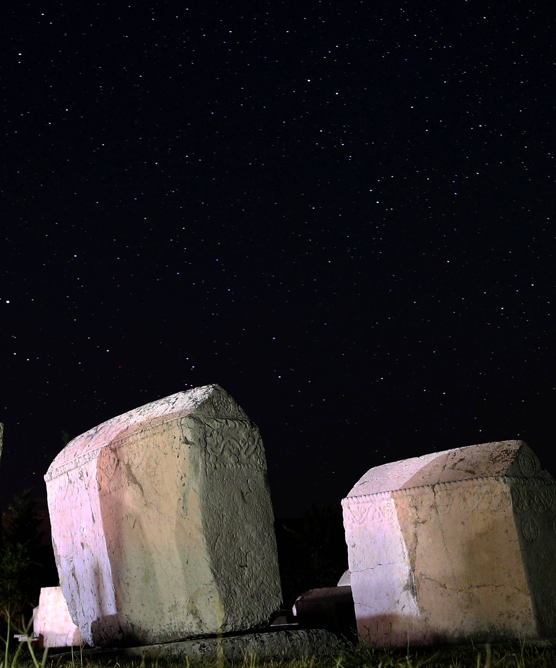 A meteor streaks past stars in the night sky above medieval tombstones in Radmilje near Stolac, south of Sarajevo