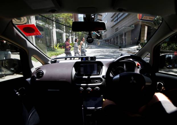 Pedestrians cross the road as a nuTonomy self-driving taxi undergoes its public trial in Singapore