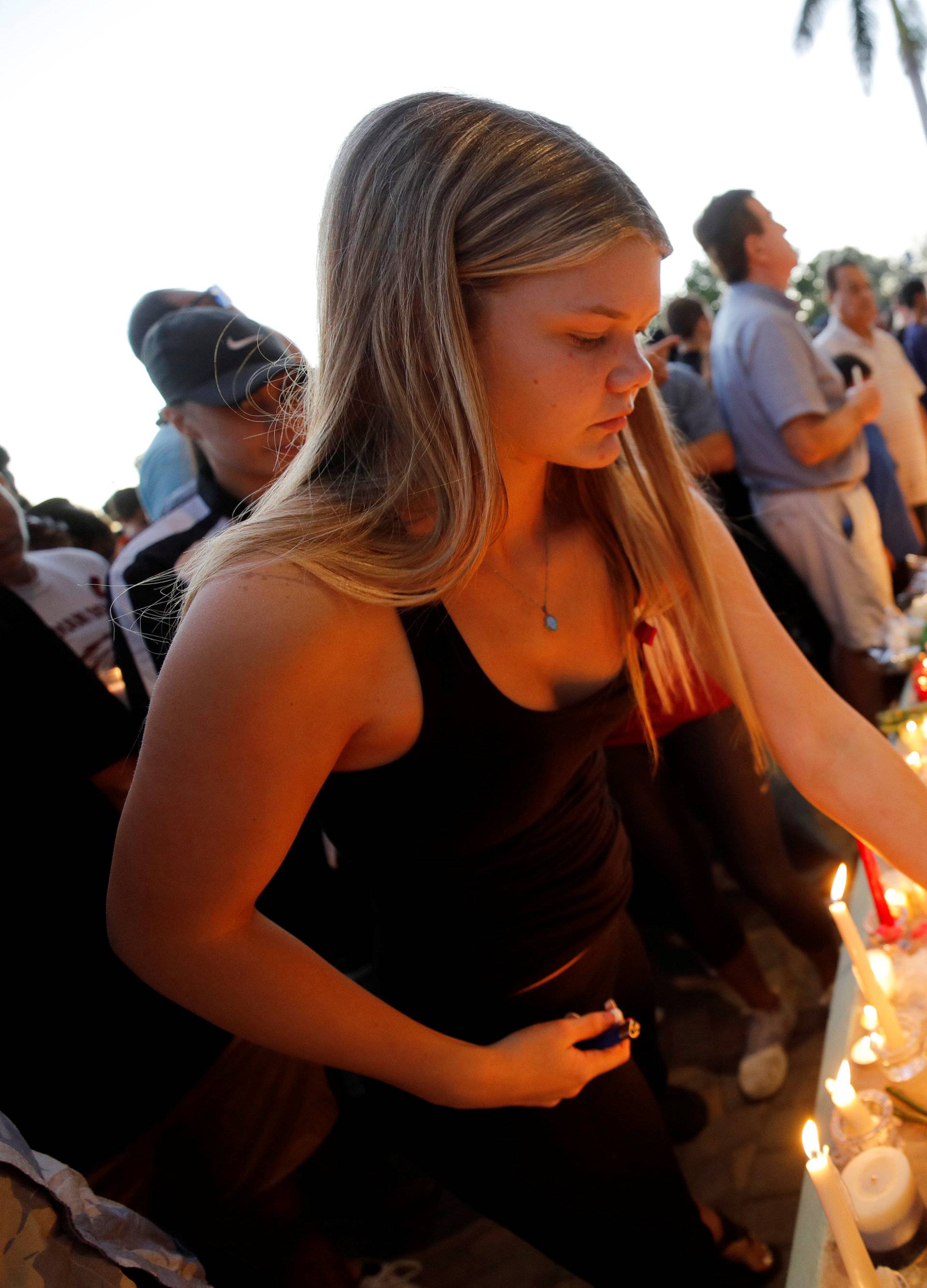 A student places a candle with other tributes at a vigil the day after a shooting at Marjory Stoneman Douglas High School in Parkland