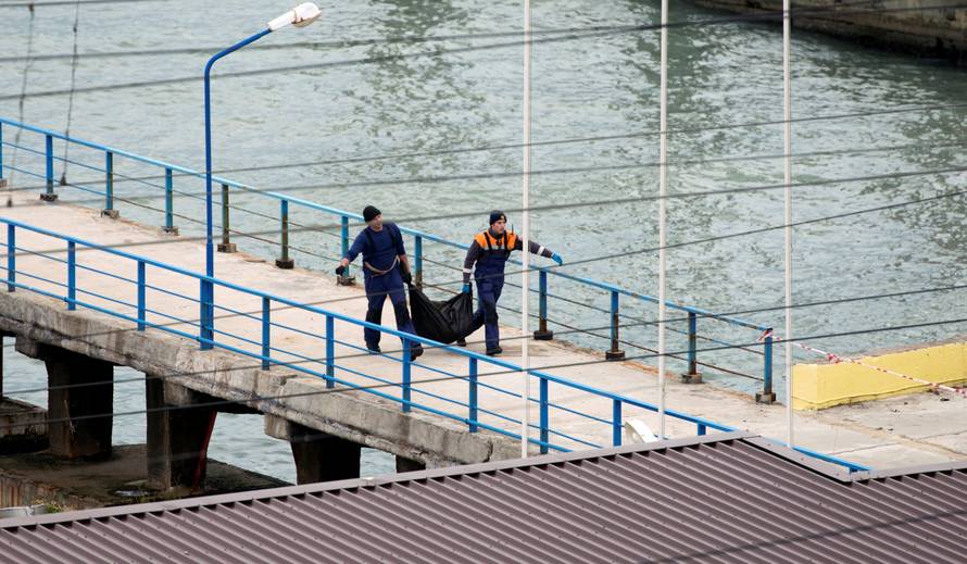 Russian Emergencies Ministry members carry plastic bag at quay of Black Sea in Sochi suburb of Khosta