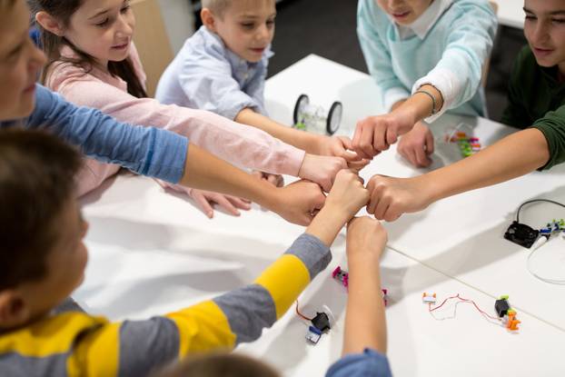 happy children making fist bump at robotics school