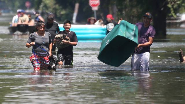 People walk with their possessions out of a flooded area of Port Arthur, Texas