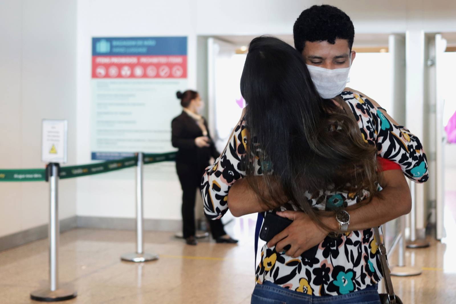 A man wearing a face mask hugs a woman amid the coronavirus disease (COVID-19) at Viracopos International Airport, in Campinas
