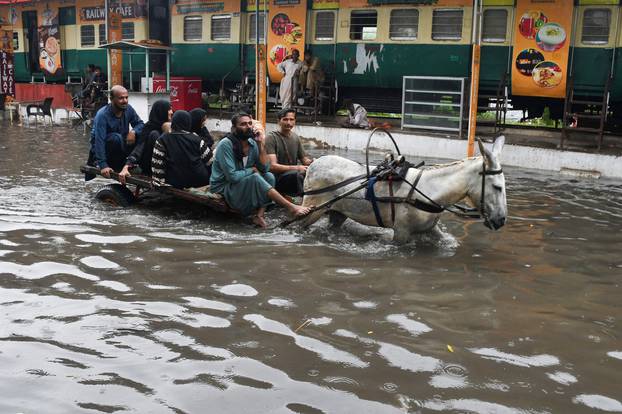 People ride on a donkey cart along a flooded road, following rains during the monsoon season in Hyderabad