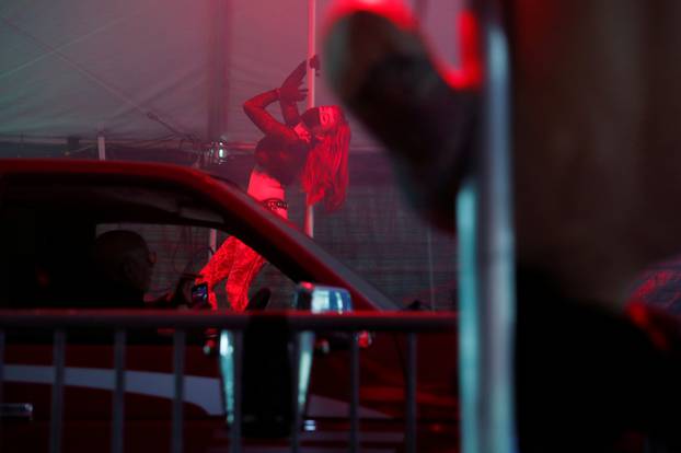 An exotic dancer wears personal protective equipment while performing in a drive-through go-go dance tent offered by the Lucky Devil Lounge strip club in Portland