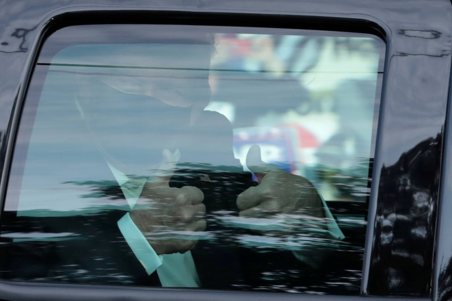 FILE PHOTO: U.S. President Donald Trump gestures from a car as he rides in front of  the Walter Reed National Military Medical Center, where he is being treated for the coronavirus disease (COVID-19) in Bethesda, Maryland