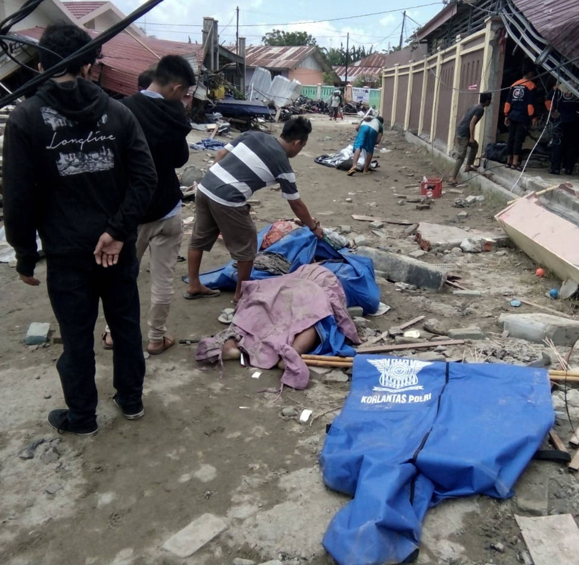 Resident checks dead bodies to find their family at a street after earthquake hit in Palu