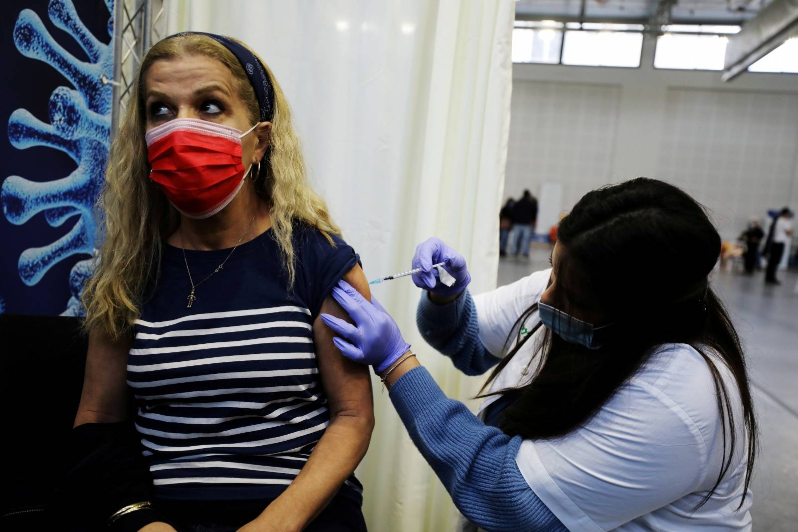 FILE PHOTO: A woman receives a vaccination against the coronavirus disease (COVID-19) at a temporary Clalit healthcare maintenance organisation (HMO) centre, at a basketball court in Petah Tikva