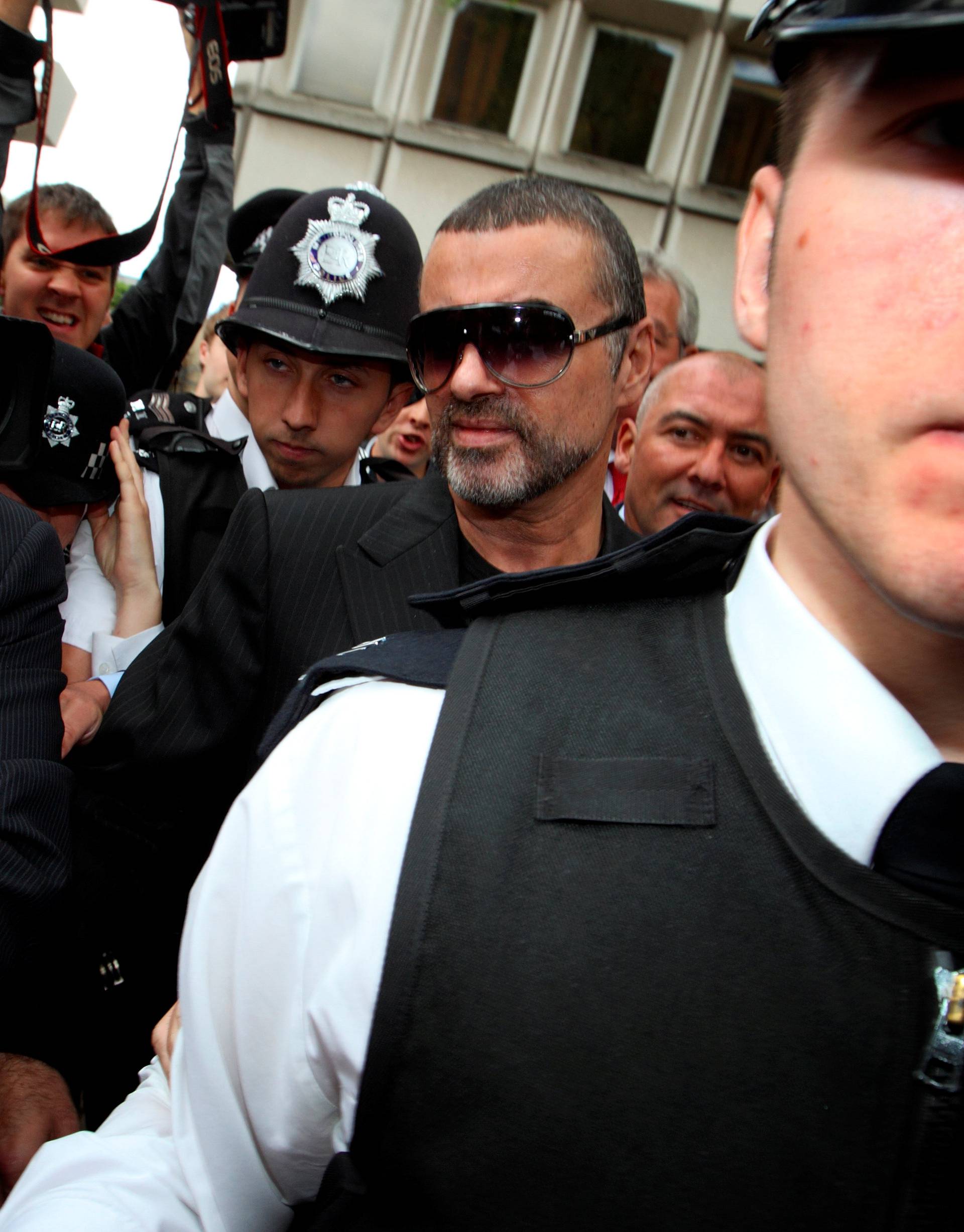 FILE PHOTO: British singer George Michael is escorted out of Highbury Corner Magistrates Court in London,