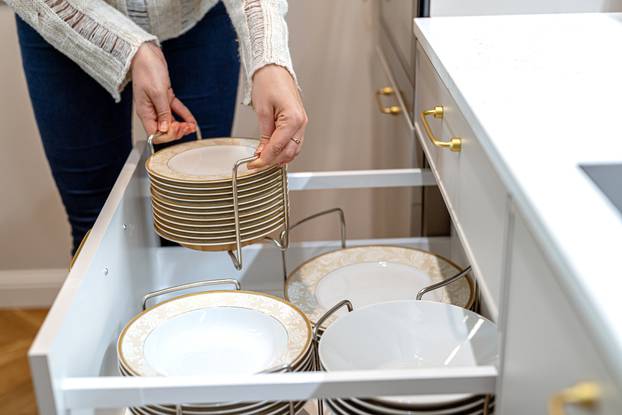 Woman,Placing,Porcelain,Plates,Into,Kitchen,Drawer.,Set,Of,Plates