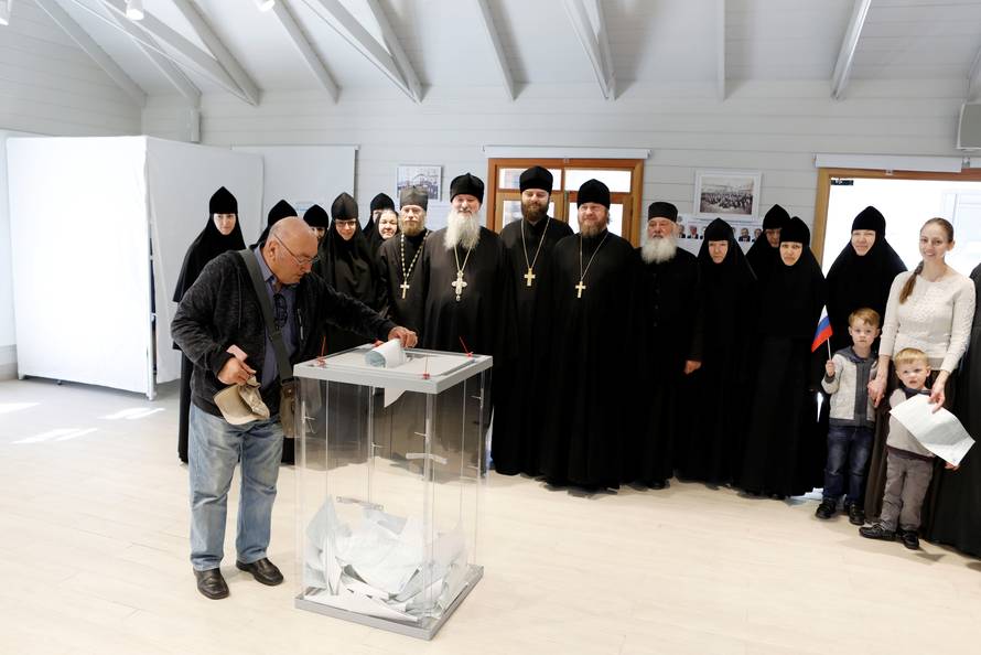 Russian clergymen and nuns pose for a group photo as a Russian citizen casts his ballot for Russia's presidential election in a polling station in Jerusalem